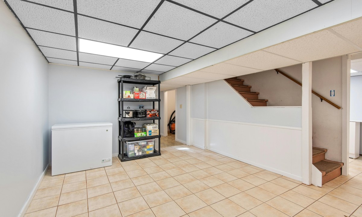 Empty basement with freezer and tiled floor
